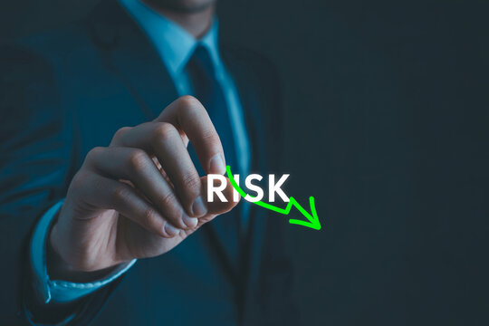 Business man pointing on risk word with arrow down concept, risk management, reduce risk.