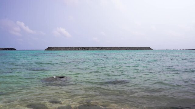 Tranquil fixed shot of a concrete breakwater on the emerald green sea at Higawa Beach in Yonaguni Island, Okinawa, Japan