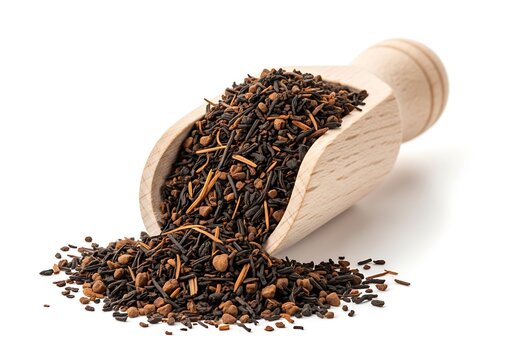 Wooden scoop overflowing with loose leaf black tea, spilling onto a white background . ctc tea