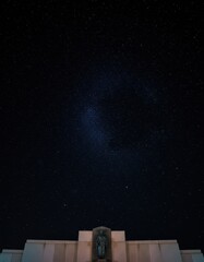 Obraz premium Starry night sky with cluster of stars shining over a stark stone memorial at night for astronomy editorial, cinematic storytelling and atmospheric background