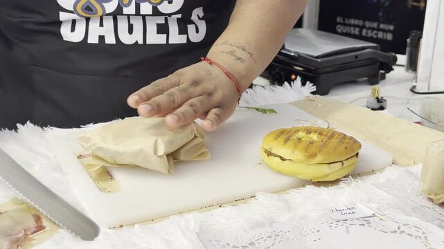 Street food worker with black gloves wrapping a freshly made bagel sandwich for a takeout order