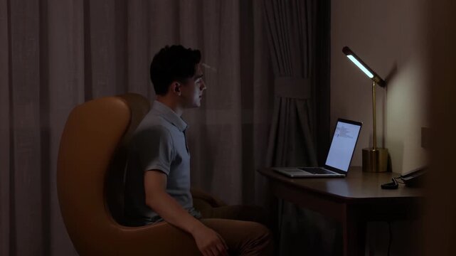 Tired businessman finished work on computer for proposal deadline, complete report or investment project while sitting at desk working late at home, stretches in chair, throwing his hand, leaning back