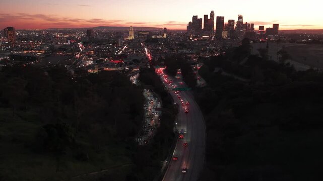 Cinematic drone footage of Los Angeles freeway at sunset with city skyline in background.