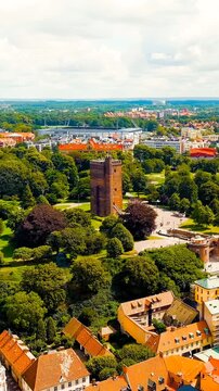 Vertical video. Helsingborg, Sweden. Karnan, the surviving 35-meter medieval keep of a Danish fortress, Drone footage over red rooftops and parkland on a partly cloudy summer day. Drone footage, Poin