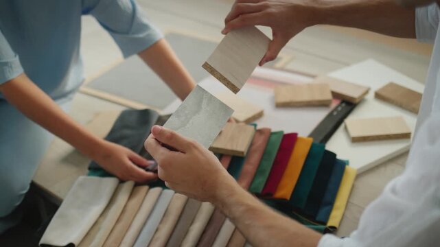 Designers choosing interior materials and fabric samples for home renovation project during creative workshop.