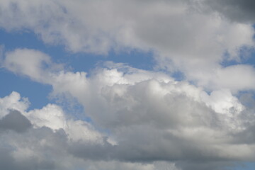 Fototapeta premium Bright clouds move across the sky in the afternoon with patches of blue peeking through