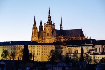 Naklejka premium As the sun sets over Prague, the majestic Prague Castle stands illuminated against the twilight sky.