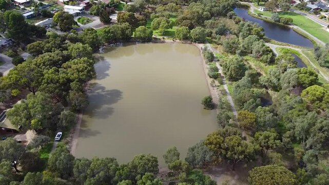 Police investigation drone footage captures divers searching a suburban dam, providing an aerial view of a potential crime scene or emergency response. This footage is suitable for news, editorial