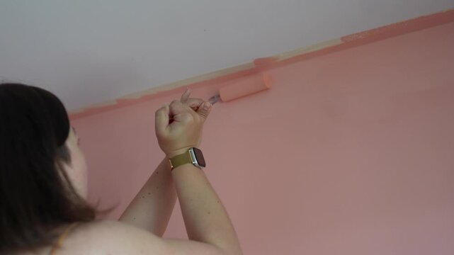 Woman paints walls in her home on a Monday afternoon