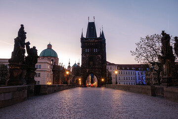 Obraz premium As dusk settles over Prague, the historic Charles Bridge reveals its stunning architecture, illuminated by warm street lights.