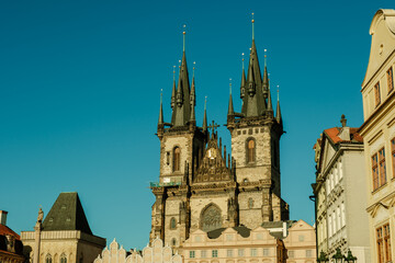 Fototapeta premium Visit the stunning architecture of Prague showcasing Gothic towers under a bright blue sky. This charming city attracts travelers seeking adventure and history during their holidays and vacations.