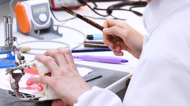 A person is engaged in the manufacture of a denture or a model of teeth.