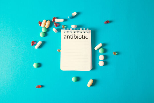 Notebook with text Antibiotics on blue background with pills.