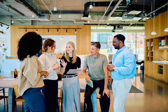 Group of diverse business people discussing ideas and collaborating in a casual meeting environment, standing and communicating