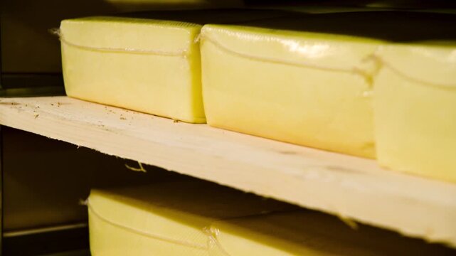 Racks filled with numerous round wheels of yellow cheese.