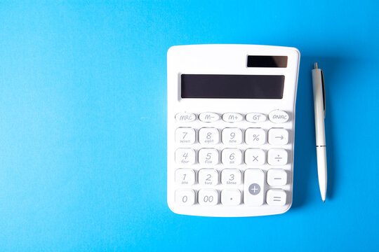 Calculator and pen on a blue background. Business concept.