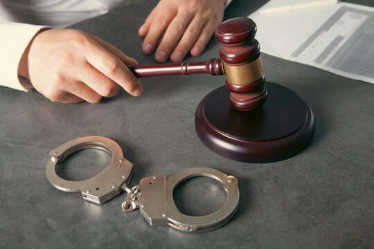 Handcuffs and judge's gavel on table, closeup