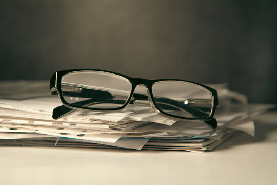 Stack of newspapers and eyeglasses