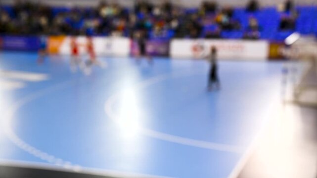 A women's sports team plays indoor handball. Blurry.