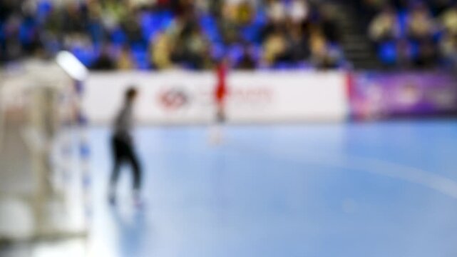A women's sports team plays indoor handball. Blurry.