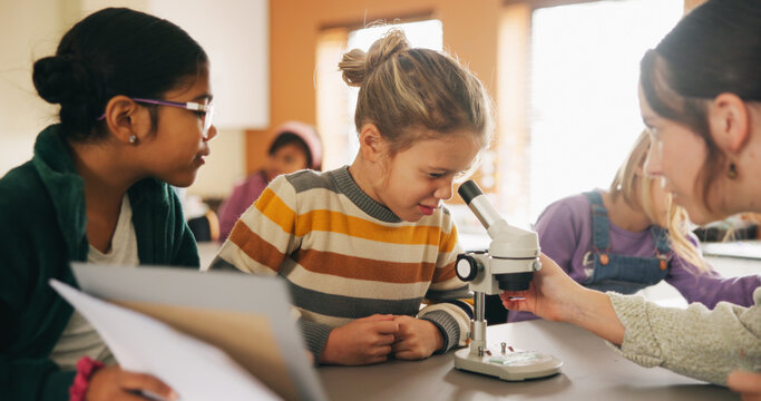 Classroom, teacher and children with microscope for learning, stem education or science lesson. Girl, students and woman teaching with equipment for project, knowledge or biology experiment in school