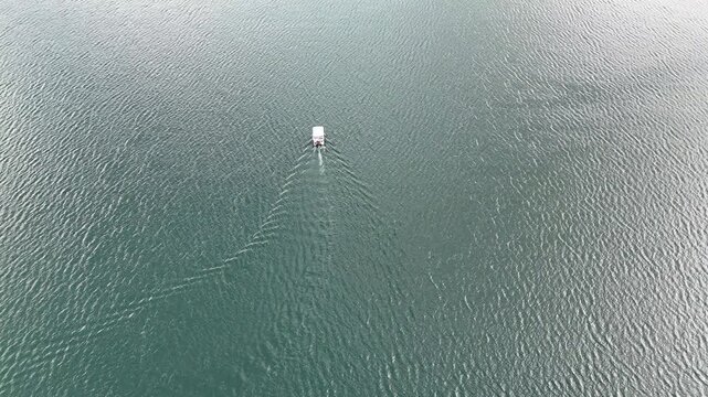 4K Drone Aerial View of Calm Mountain Lake With Small Floating Boat and Water Texture.