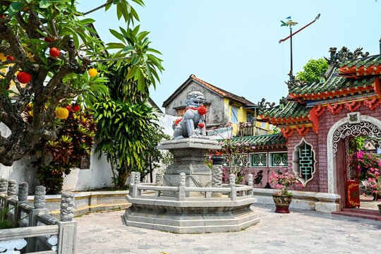 HOI AN, VIETNAM, APRIL 19, 2026 Traditional stone lion statue at inner courtyard next to ornate gate of the Fujian Assembly Hall temple