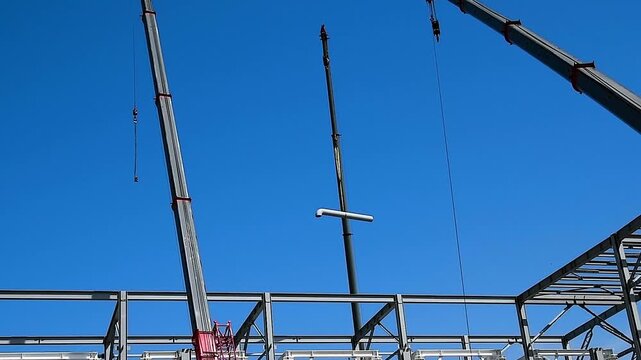 A construction crane with a long boom is used for lifting and installing metal structures.