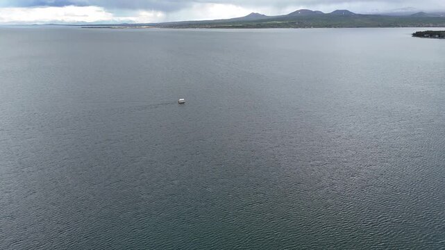 4K Drone Aerial View of Calm Mountain Lake With Small Floating Boat and Water Texture.