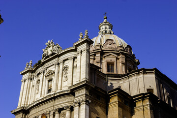 Obraz premium The dome and facade of the Church of Santi Vincenzo e Anastasio a Trevi in Rome, Italy, under a clear blue sky.
