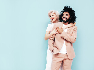 Fototapeta premium Smiling beautiful woman and her handsome boyfriend. Sexy cheerful multiracial family having tender moments on blue background in studio. Multiethnic models hugging. Embracing each other.Love concept