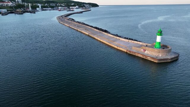 Aerial footage of green harbor entrance beacon located at the end of the breakwater in Sassnitz on Rugen Island, Germany. Maritime navigation aid marking the harbor entrance on the Baltic Sea coast.