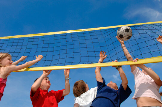 Children (6-9) playing volleyball, low angle view