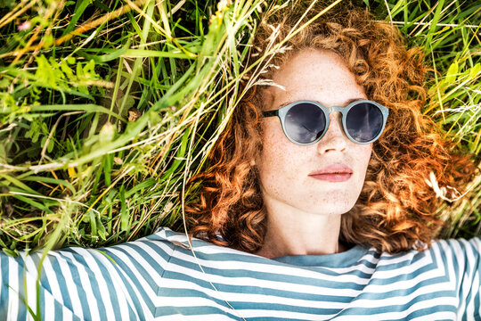 Portrait of young woman relaxing on a meadow wearing sunglasses