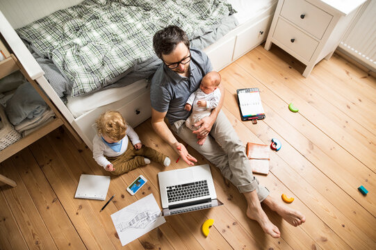 Father with his little son and baby daughter working from home