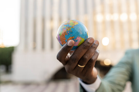 Hand of mature businessman holding globe figurine