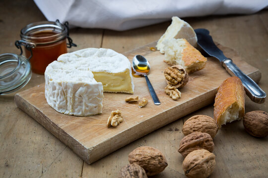 Camembert, bread, walnuts and honey on wood