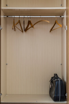 Empty coat hangers and an old-fashioned travel bag in a closet