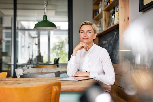 Portrait of confident blond woman sitting at table