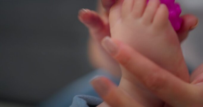 Close-up views of an adult holding a baby's foot and a pink textured toy, highlighting gentle interaction and sensory play between caregiver and infant in a calm indoor setting