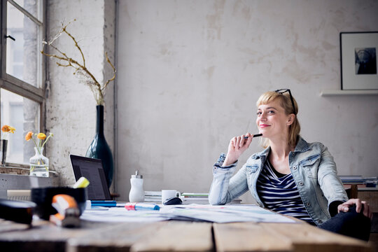 Portrait of smiling woman sitting at desk in a loft