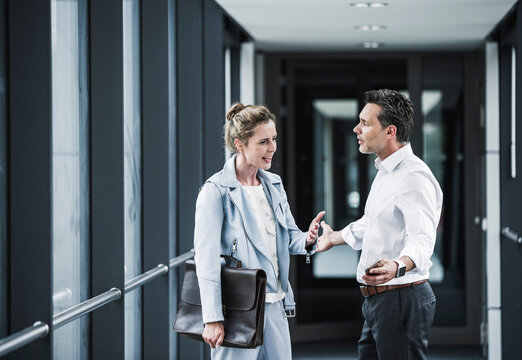 Businesswoman and businessman arguing in office passageway