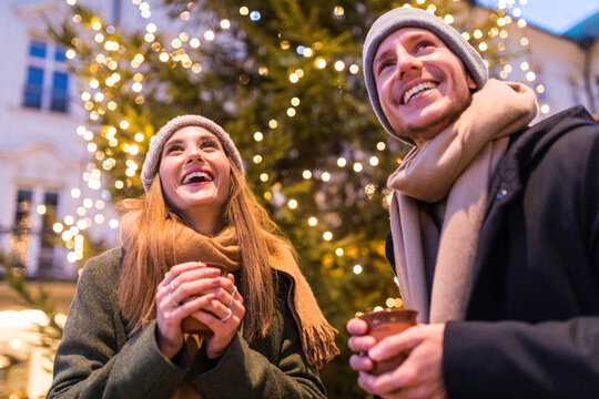 Laughing young couple drinking mulled wine at Christmas market