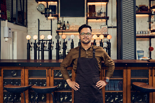 Portrait of a confident waiter at the counter in a pub