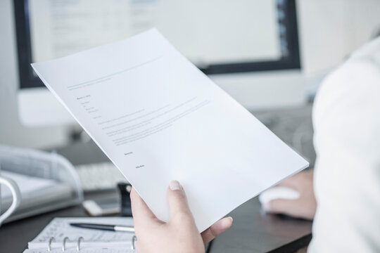 Close-up of woman at desk holding a document