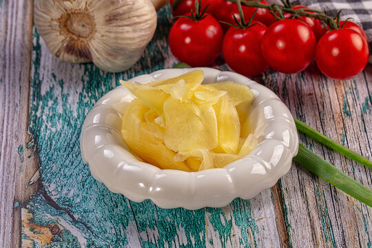 Pickled ginger gari in white bowl with fresh vegetables on rustic wood