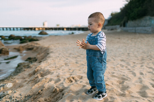 Toddler standing alone on sandy beach near the sea