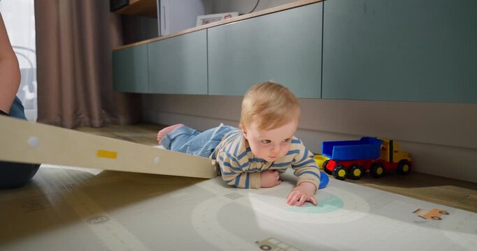 A young toddler crawling and exploring a play mat on the floor while engaging in early motor skill development and interactive play in a modern home environment