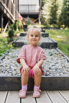 Cute toddler girl smiling while sitting on outdoor steps