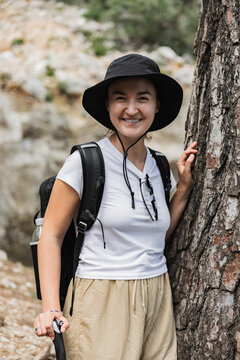 Smiling hiker takes a break by a tree